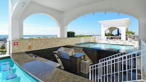 An outdoor pool area with a barbecue and a view of the ocean. - Emerald 705 by Ryson Vacation Rentals (Galveston)