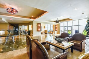 A spacious lobby with a high ceiling, a central seating area, and large windows allowing natural light. - Emerald 705 by Ryson Vacation Rentals (Galveston)