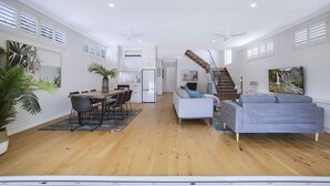 A spacious living area with a dining table, sofas, and a staircase leading to an upper level. - Manly Oasis, 5bd, 3 King bd,Pool (Manly)