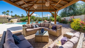 Un espacio de estar techado al aire libre con muebles de mimbre y una piscina al fondo.