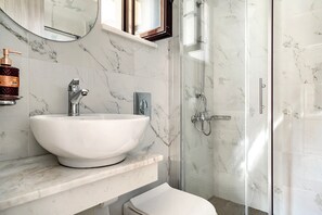 Une salle de bain avec un lavabo blanc, un miroir et une cabine de douche en verre.