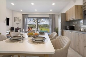 A modern dining area with a large table, chairs, and a view of the outdoors.