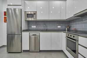 Una cocina moderna con electrodomésticos de acero inoxidable, lavavajillas, microondas y horno empotrado.