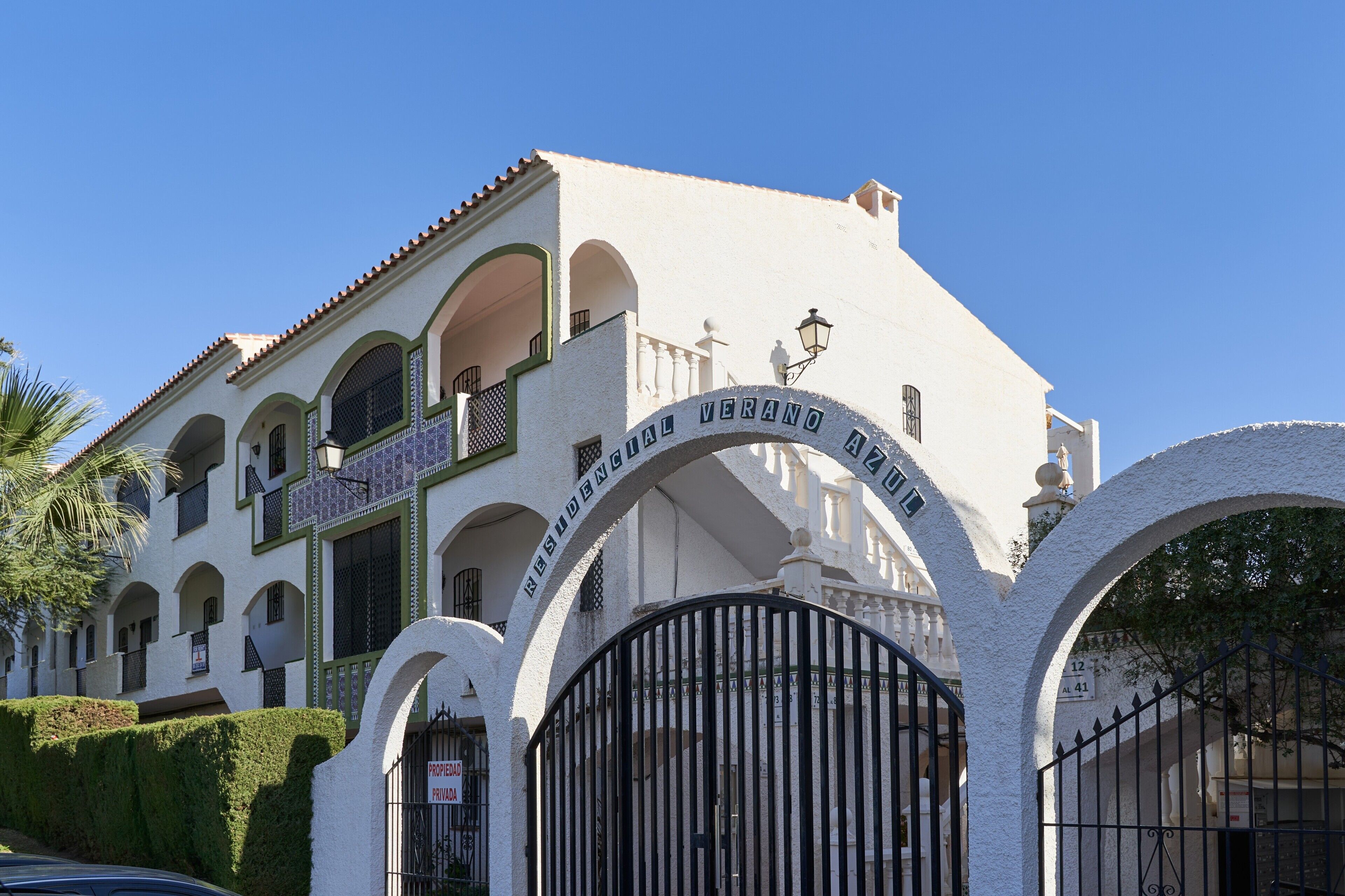 A white building with arched windows and a sign that reads 'Hotel Verano Azul.'