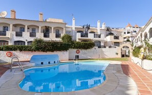 Una piscina con borde de piedra, un flotador salvavidas y una escalera de metal.