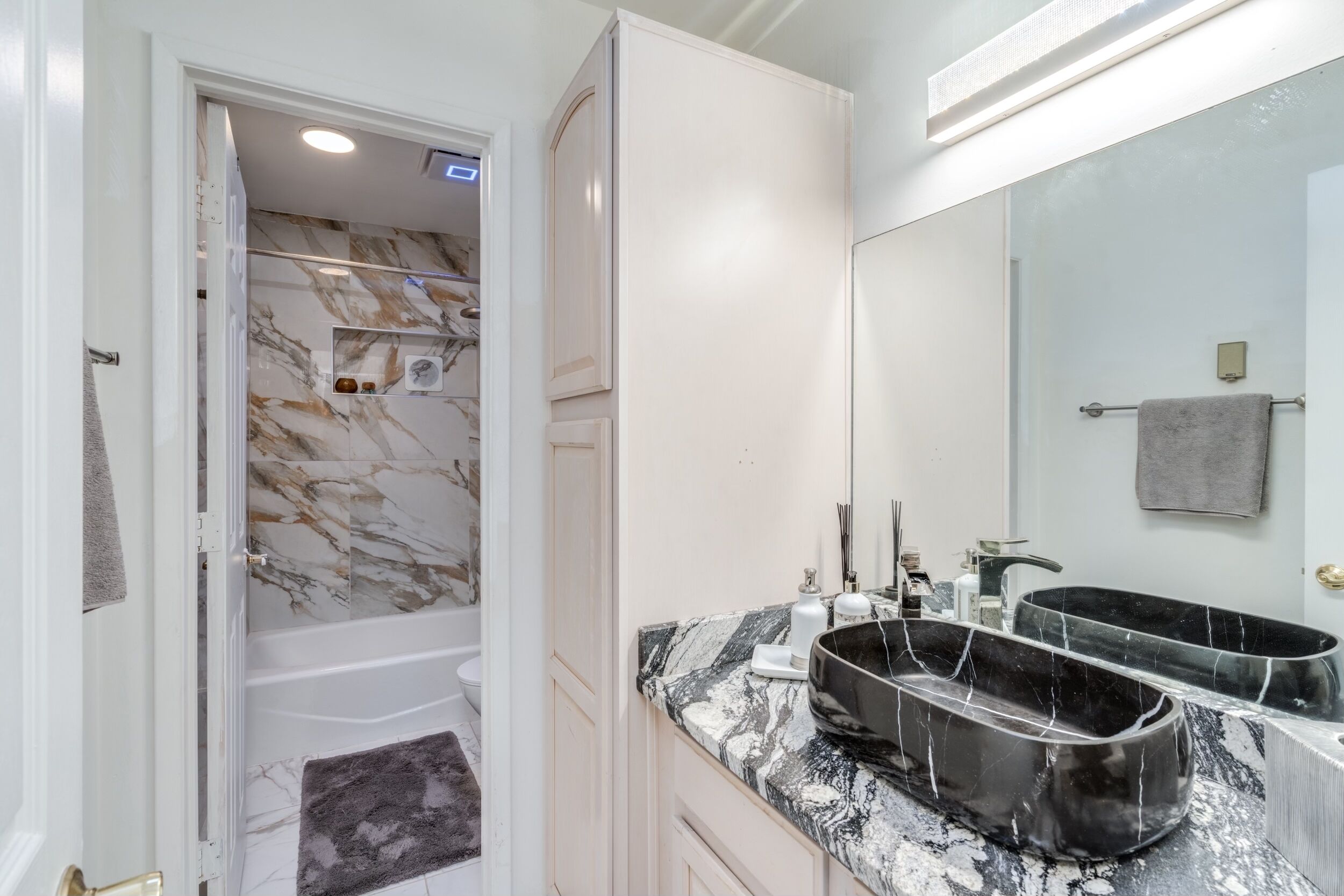 Une salle de bain moderne avec un meuble-lavabo en marbre, deux vasques et un grand miroir.