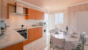 A modern kitchen with a dining area, built-in oven, microwave, and washing machine. - Clemente House, Private Pool – Sea Views, Private Terrace, and Wi-Fi (arafo)