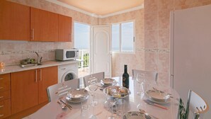 A kitchen with a dining area, a washing machine, and a view through a door. - Clemente House, Private Pool – Sea Views, Private Terrace, and Wi-Fi (arafo)