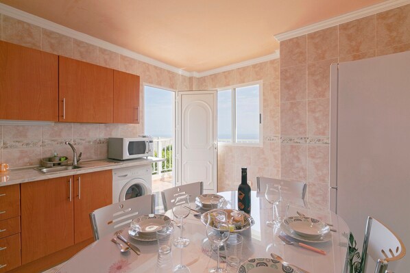 A kitchen with a dining area, a washing machine, and a view through a door.