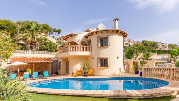 Uma casa de dois andares com piscina, varanda e jardim.