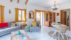 Sala de estar com sofá, poltrona, mesa de centro e canto de jantar com cadeiras.