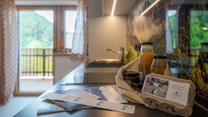 A hotel room with a view of greenery, a counter with a menu, and a small table with a tray containing a drink and a menu. - Farm 'Enzian' with Mountain View, Shared Terrace and Wi-Fi (Funes)