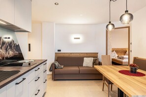 Una cocina moderna con estufa, armarios y un comedor con mesa y sillas de madera.