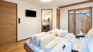A bedroom with a bed, wooden door, television, and a wooden-framed window. - Holiday Apartment "Planerhof Apartment Alpenrose" with Mountain View, Shared Terrace, and Wi-Fi (Funes)