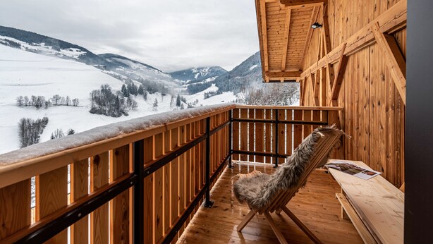 A wooden balcony with a chair and a bench, overlooking a snowy landscape with mountains. - Holiday Apartment "Planerhof Apartment Alpenrose" with Mountain View, Shared Terrace, and Wi-Fi (Funes)