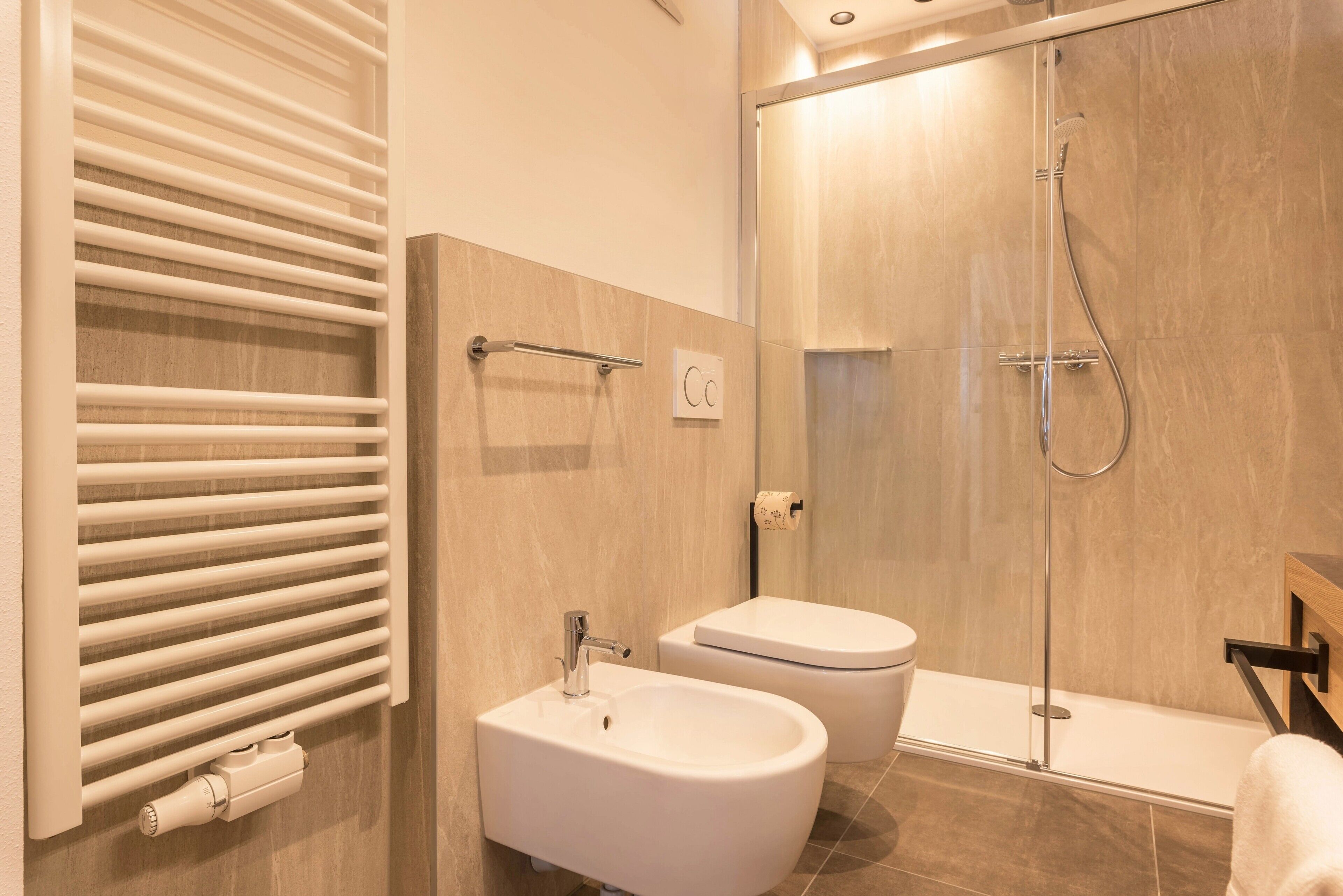 Et moderne badeværelse med bidet, toilet og bruseniche.