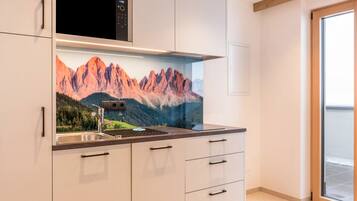 A modern kitchen with a mountain mural, stainless steel appliances, and a sliding glass door.