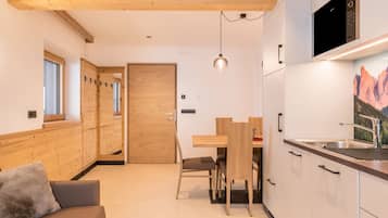 Een moderne keuken met houten kastjes, een ingebouwde magnetron en een eethoek met een houten tafel en stoelen.