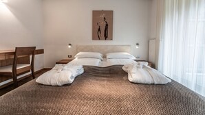 A bedroom with a large bed, two bedside tables, a chair, a painting on the wall, and a window with curtains. - Apartment "Le Table C" with Mountain View, Garden & Wi-Fi (St. Vigil in Enneberg)