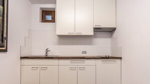 A kitchen with white cabinets, a wooden countertop, a window, and a small skylight. - Apartment "Le Table C" with Mountain View, Garden & Wi-Fi (St. Vigil in Enneberg)