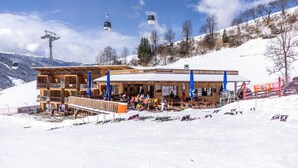 A wooden building with a restaurant, ski lift, and snow-covered landscape. - Apartment "Le Table E" with Mountain View, Garden & Wi-Fi (St. Vigil in Enneberg)