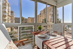 A balcony with a table set for dining, a potted plant, and a view of high-rise buildings.