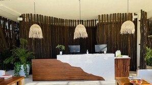 A reception area with a wooden reception desk, two television monitors, and a large potted plant. - TULUM loft in the Heart of Aldea Zama (Tulum)