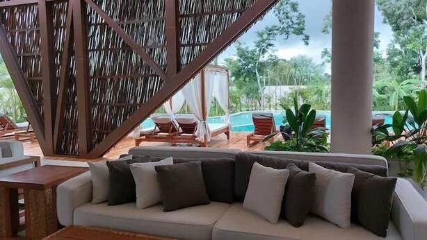 A lounge area with a sofa, a pool, and outdoor seating. - TULUM loft in the Heart of Aldea Zama (Tulum)