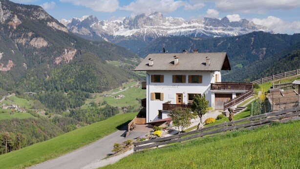 A two-story house with a balcony, set against a mountainous backdrop. - Apartment 'Rosengartenblick' with Terrace, Balcony and Wi-Fi (Steinegg)