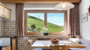 A kitchen with a window view, wooden furniture, and a tiled backsplash. - Apartment 'Rosengartenblick' with Terrace, Balcony and Wi-Fi (Steinegg)