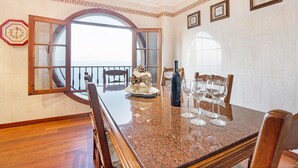 A dining area with a marble table, chairs, a decorative centerpiece, and a large window with a view. - Vacation Home "La Victoria' with Sea View, Private Terrace & Wi-Fi (La Victoria)