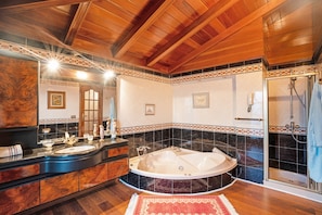 A bathroom with a wooden ceiling, a large bathtub, a shower, and a vanity with a mirror.
