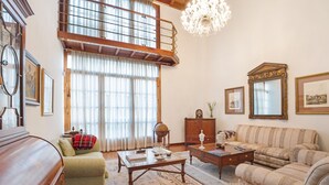 A spacious living room with a high ceiling, a wooden staircase, and a chandelier. - Vacation Home "La Victoria' with Sea View, Private Terrace & Wi-Fi (La Victoria)