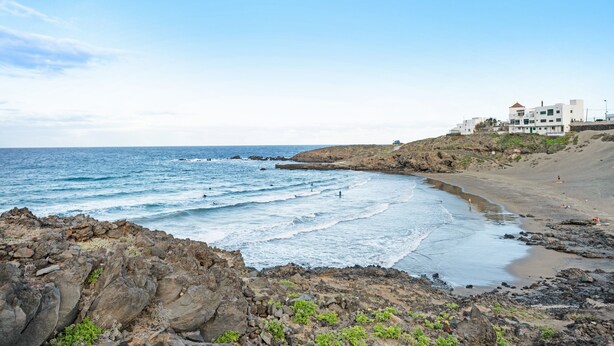 A coastal landscape with rocky terrain, a beach, and a building with multiple floors and balconies. - Holiday Apartment "Poris" with Heated Pool, Private Terrace & Wi-Fi (Arico)