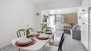 A dining area with a table set for four, chairs, a sofa, and a kitchen in the background. - Holiday Apartment "Poris" with Heated Pool, Private Terrace & Wi-Fi (Arico)