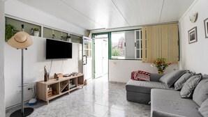 A living room with a grey sofa, a TV mounted on the wall, a wooden cabinet, and a floor lamp. - Holiday Apartment "Poris" with Heated Pool, Private Terrace & Wi-Fi (Arico)