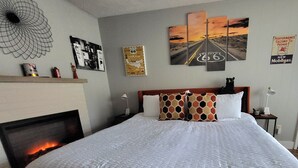 Ein Hotelzimmer mit einem großen Bett, einem Kamin und Wandbildern, darunter Route 66.