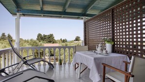 A covered outdoor seating area with a table and chairs, a view of the landscape, and a wooden lattice partition. - Studio Apartment "Areti Orfeas Studio" near Beach with Balcony & Wi-Fi (Zakynthos)