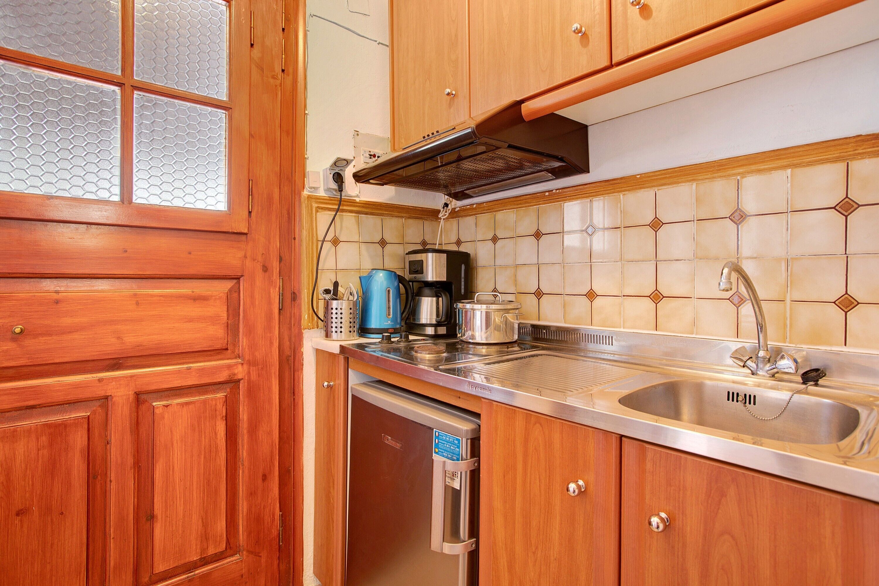 Una cocina con armarios de madera, un lavamanos de acero inoxidable, una cafetera y un lavavajillas.