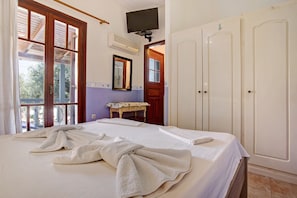 Une chambre d’hôtel équipée d’un lit, d’une télévision, d’une armoire et d’une salle de bain avec un miroir et un porte-serviettes.