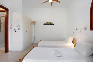 Ein Schlafzimmer mit zwei Betten, einem Deckenventilator, einem Traumfänger und einem Bild an der Wand.