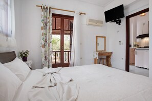 Une chambre à coucher avec un lit, un bureau, une télévision et une vue sur l’extérieur.