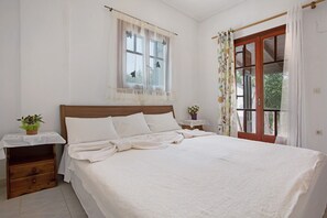 A bedroom with a bed, a nightstand, a window with curtains, and a door with a view. - Holiday Apartment "Areti Orfeas Apartment 3" near Beach with Balcony & Wi-Fi (Zakynthos)