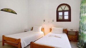 A room with two wooden beds, a small window, and a wall-mounted light fixture.