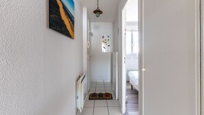 A hallway with a radiator, a door leading to a bedroom, and a welcome mat. - Apartment "Didier" with Sea View, Terrace & Wi-Fi (Mimizan)