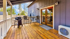 A covered outdoor area with a grill, two chairs, a table, and a sliding glass door leading to an interior space. - Lake View Hideaway Near Yosemite & Bass Lake (Oakhurst)