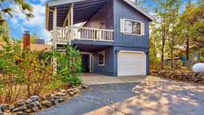 A two-story house with a balcony, garage, and stone wall. - Lake View Hideaway Near Yosemite & Bass Lake (Oakhurst)