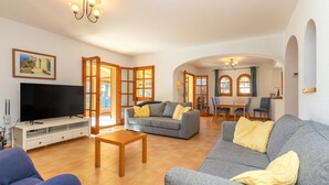 A living room with a TV, sofas, and a dining area. - Villa "Rosa" with Mountain View, Pool & Wi-Fi (Calonge)