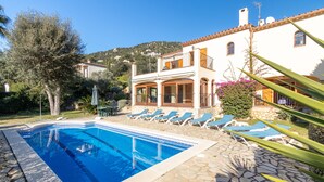 A pool with lounge chairs, a two-story building, and a mountainous backdrop. - Villa "Rosa" with Mountain View, Pool & Wi-Fi (Calonge)