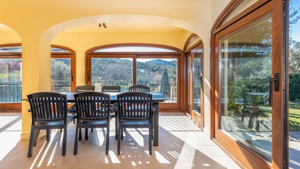 A dining area with a table and chairs, large windows, and a view of the outdoors. - Villa "Rosa" with Mountain View, Pool & Wi-Fi (Calonge)